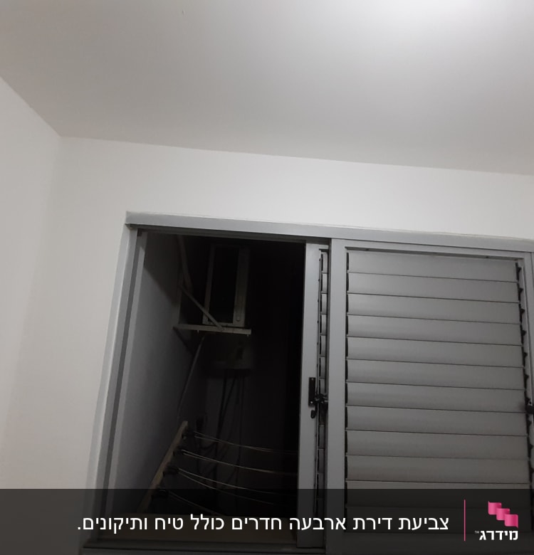חלון עם תריסים אפורים על קיר לבן